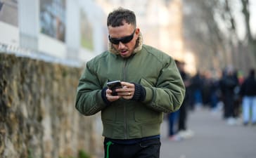 Man walking outdoors while using a smartphone.