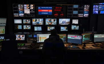 Employee facing broadcast monitors in Deutsche Welle’s Berlin control room
