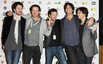 Powderfinger’s five members posing together with an award at the 2010 ARIA Awards.