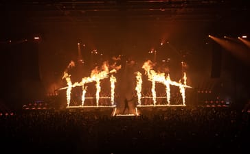 Parkway Drive vocalist Winston McCall performs on stage surrounded by flames and pyrotechnics.