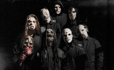 Slipknot members wearing masks and black outfits against a dark background.
