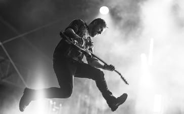 Ben Weinman leaps into the air while playing guitar at Brutal Assault in 2017.