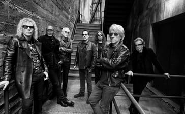 Bon Jovi pose together on an outdoor metal staircase in a black-and-white promotional photograph.