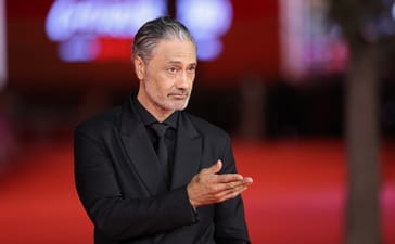 Taika Waititi poses in a black suit on the red carpet at the Rome Film Festival.