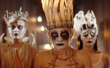 Three Witch Club Satan members wearing black and white face paint and elaborate crowns.