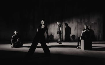 Reliqa pose in a dimly lit concrete space, with long shadows behind the four band members.