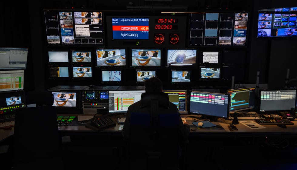 Employee facing broadcast monitors in Deutsche Welle’s Berlin control room