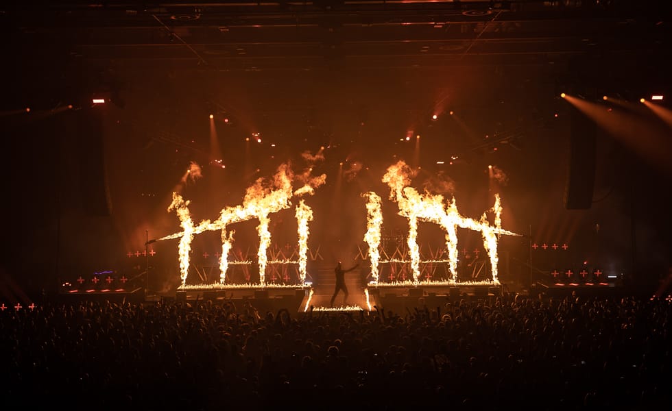 Parkway Drive vocalist Winston McCall performs on stage surrounded by flames and pyrotechnics.