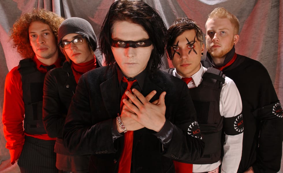 My Chemical Romance pose in red, black and white outfits, with Gerard Way at the centre, his hands crossed over his chest.