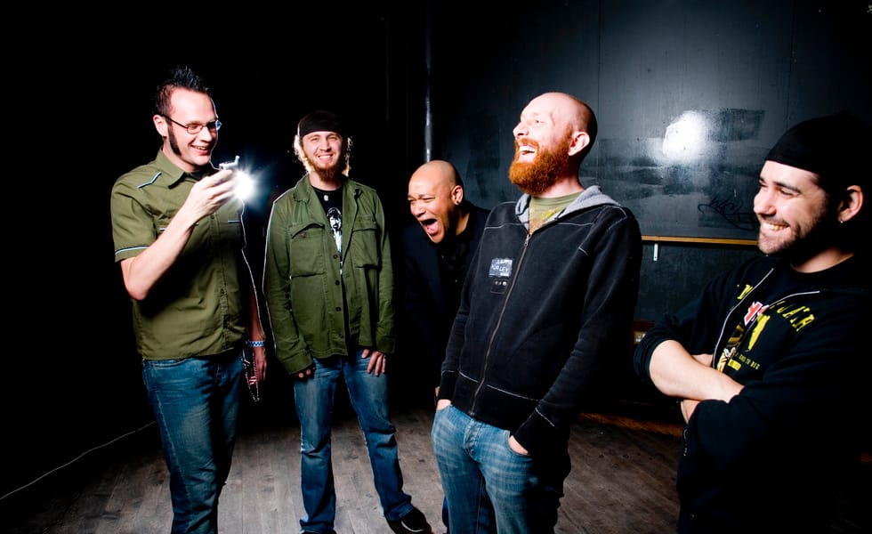 Killswitch Engage members laughing together, with Adam Dutkiewicz at left and Howard Jones in the centre.