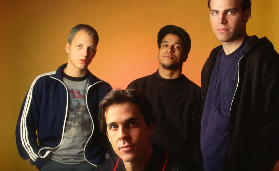 Four members of Quicksand posing against an orange background.