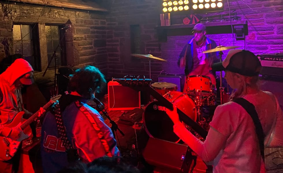 They Are Gutting A Body Of Water performing together under red and purple lighting in a stone-walled venue.