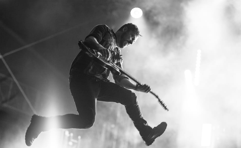 Ben Weinman leaps into the air while playing guitar at Brutal Assault in 2017.