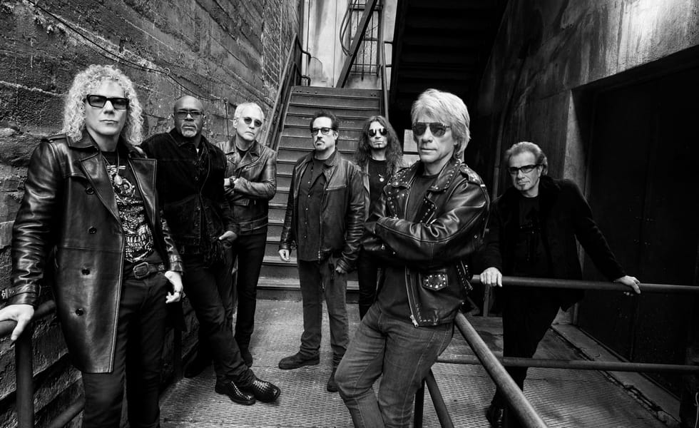 Bon Jovi pose together on an outdoor metal staircase in a black-and-white promotional photograph.