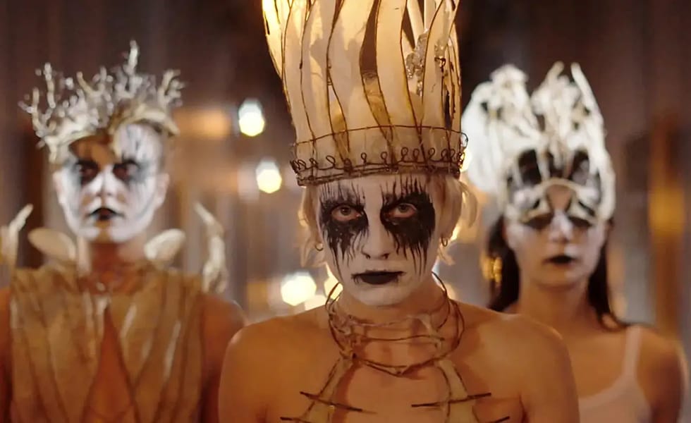 Three Witch Club Satan members wearing black and white face paint and elaborate crowns.
