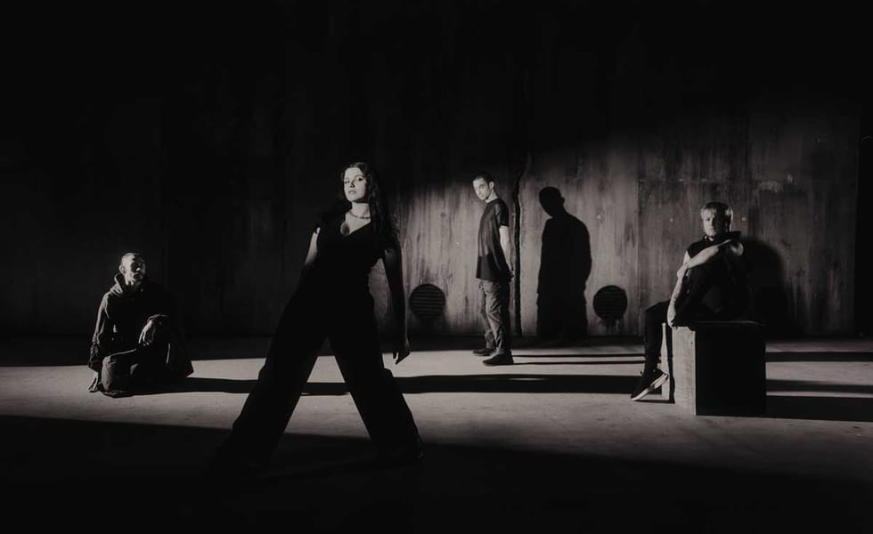 Reliqa pose in a dimly lit concrete space, with long shadows behind the four band members.
