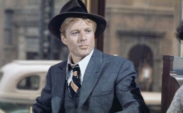 American actor Robert Redford wearing a grey tweed blazer over a matching waistcoat and a white shirt, with a diagonally striped tie, with a grey fedora, in a scene from 'The Sting', filmed in the United States, 1973. The crime caper directed by George Roy Hill, starred Redford as Johnny Hooker. (Photo by Archives/Getty Images)